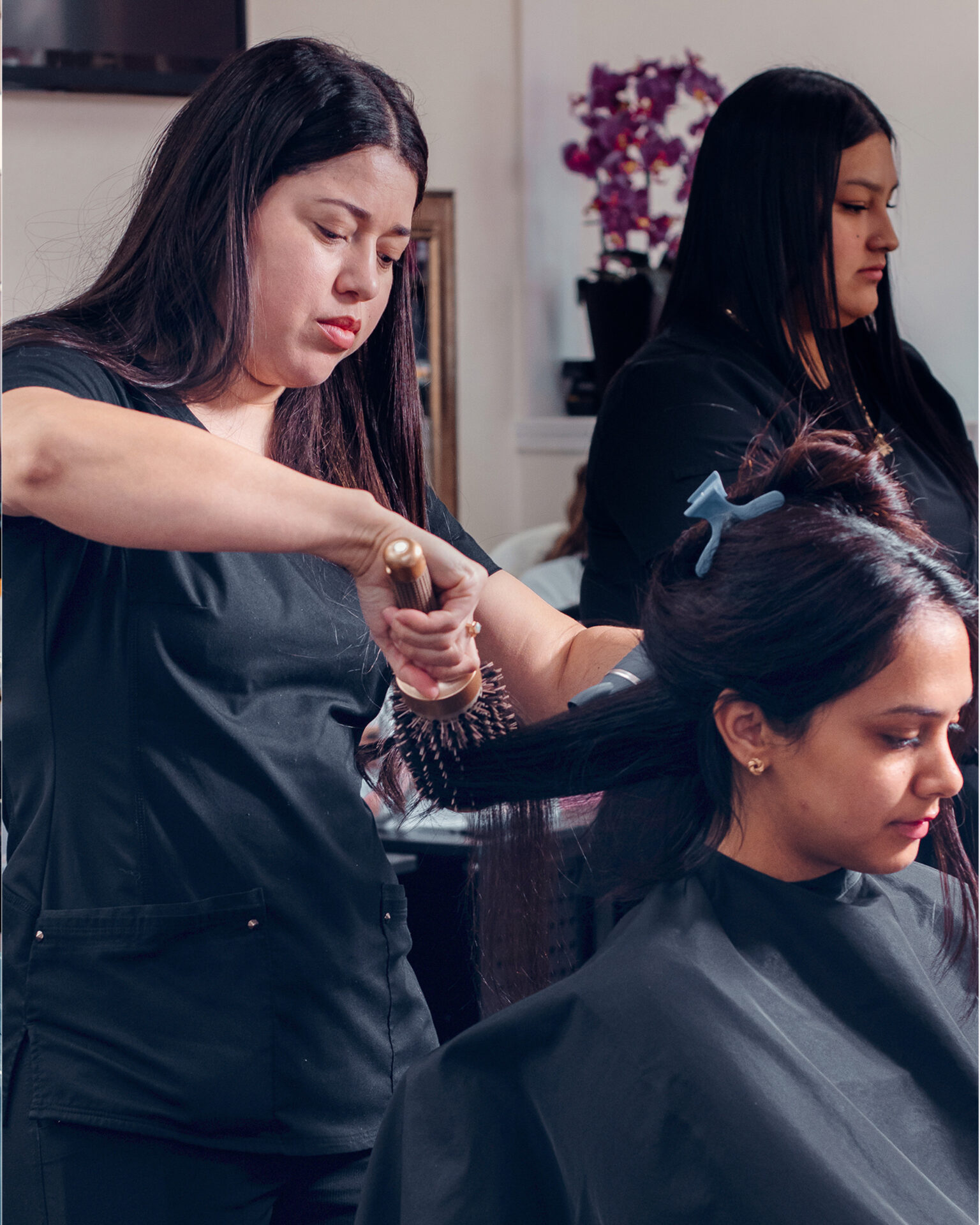 Instructora de R&C Beauty College guiando a una estudiante en práctica de peinado